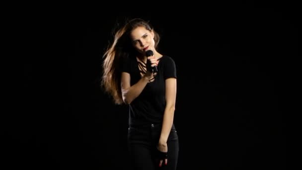 Menina dança e canta em um concerto de rock, seu corpo é sexy. Fundo preto — Vídeo de Stock