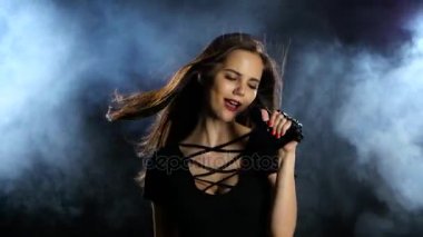 Şarkıcı cinsel dans ediyor ve bir mikrofon bir konserinde şarkı söylüyor. Siyah duman arka plan