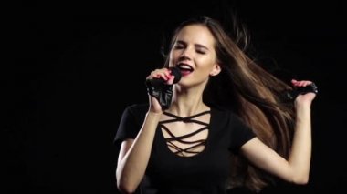 Kız bir mikrofon sürüş gülümser ve şarkı söylüyor. Siyah arka plan. Ağır çekim