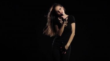 Kız dans etmek ve şarkı söyler bir rock konserinde, vücudu seksidir. Siyah arka plan. Ağır çekim