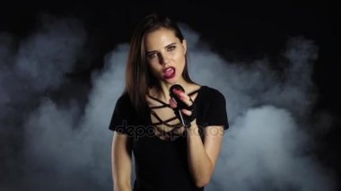 Şarkıcı cinsel dans ediyor ve bir mikrofon bir konserinde şarkı söylüyor. Siyah duman arka plan. Ağır çekim