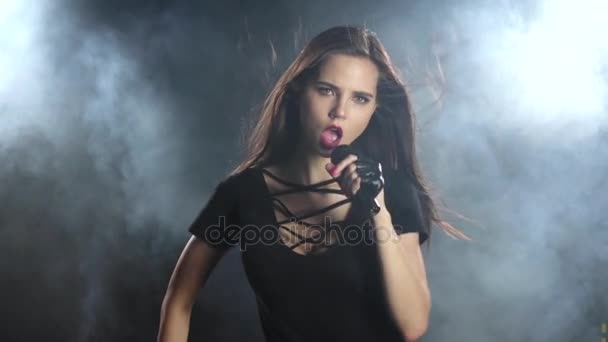 Şarkıcı cinsel dans ediyor ve bir mikrofon bir konserinde şarkı söylüyor. Siyah duman arka plan. Ağır çekim — Stok video