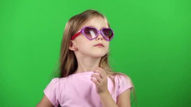 Küçük kız gözlük ile video kameralar için poz. Yeşil ekran. Ağır çekim