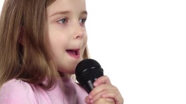 Küçük kız mikrofona şarkı söyler. Beyaz arka plan. Yakın çekim. Ağır çekim