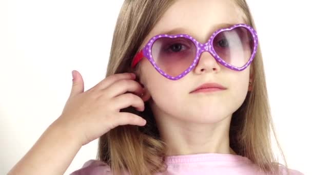 Bébé posant pour les caméras vidéo avec des lunettes. Fond blanc. Ferme là. Mouvement lent — Video