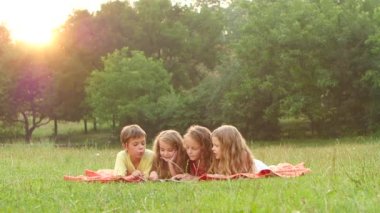 Mutlu çocuk bahçesinde bir kitap yaz günde çimenlikte aracılığıyla yaprak. Ağır çekim