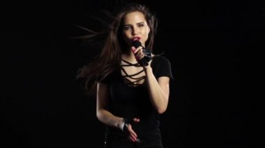 Kız mikrofon hassas şarkıları shes karizmatik söylüyor. Siyah arka plan. Ağır çekim