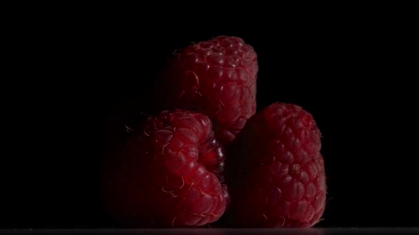 La fruta de frambuesa gira sobre un fondo negro. De cerca. — Vídeos de Stock