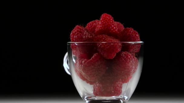 Vitamine raspberry dessert in een transparante beker draait op een zwarte achtergrond. Close-up — Stockvideo