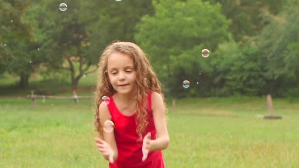 Ragazza che gioca bolle di sapone cattura sul giardino. Al rallentatore. Da vicino. — Video Stock