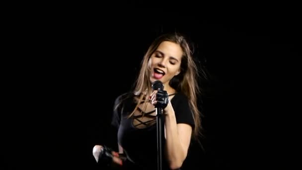 Τραγουδιστής σεξουαλικά χορεύει και τραγουδάει τα τραγούδια σε ένα μικρόφωνο σε μια συναυλία. Μαύρο φόντο — Αρχείο Βίντεο