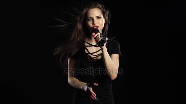 Το κορίτσι που τραγουδάει σε τα τραγούδια ευαίσθητο μικρόφωνο, shes χαρισματικού. Μαύρο φόντο. Αργή κίνηση — Αρχείο Βίντεο