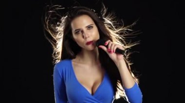 Mavi frank top kız mikrofona doğru söylüyor. Siyah arka plan. Ağır çekim