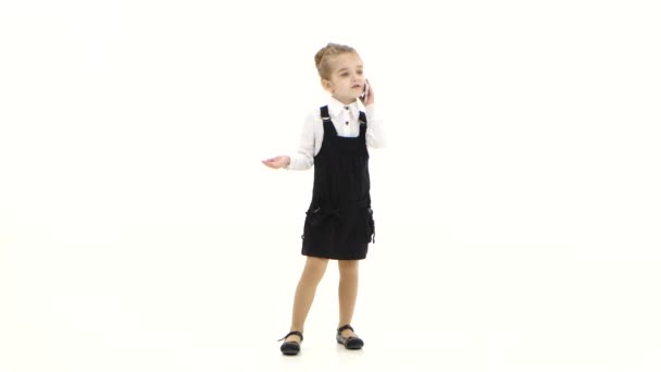 Školy dívka prvňáček komunikuje prostřednictvím mobilního telefonu, bílé pozadí — Stock video
