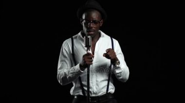 Adam şarkıcı şarkı söylüyor bir mikrofon ve dans içine. Siyah arka plan. Ağır çekim