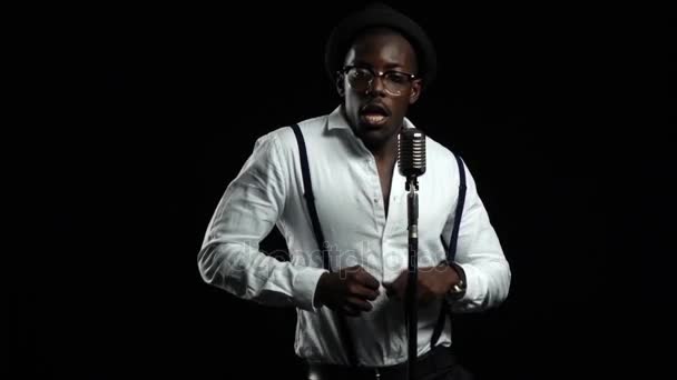 Αρσενικό Αφρικανικός Αμερικανός τραγουδιστής τραγουδά σε ένα μικρόφωνο και χορό. Μαύρο φόντο. Αργή κίνηση. Κοντινό πλάνο — Αρχείο Βίντεο