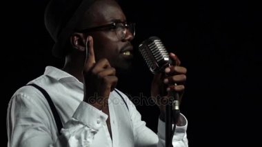 Retro bir mikrofon ve yanında dans içine şarkıcı söylüyor. Siyah arka plan. Ağır çekim. Yakın çekim