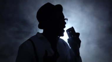Devir oranı, duman yarısı adam ve beyaz ışık mikrofon şarkı. Siyah arka plan. Siluet. Ağır çekim. Yakın çekim