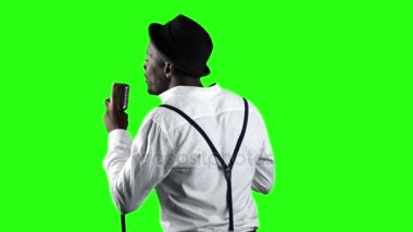 Şarkıcı arka görünümünden retro bir mikrofon ve yanında dans şarkı söylüyor. Yeşil ekran. Ağır çekim. Yakın çekim