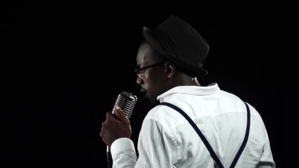 African American musician the view from the back singing in a studio. Black background. Slow motion. Close up — Stock Video