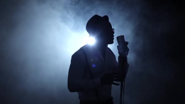 Sänger die Hälfte des Umsatzes im rauchig-weißen Licht am Mikrofon singend. schwarzer Hintergrund. Silhouette. Zeitlupe — Stockvideo