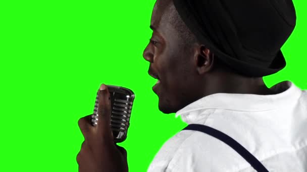 Uomo giovane afroamericano la vista dal retro si avvicina al microfono cantando in uno studio di registrazione. Schermo verde. Al rallentatore. Da vicino. — Video Stock