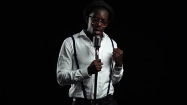 İplik ve onun etrafında dans retro bir mikrofona şarkıcı söylüyor. Siyah arka plan. Ağır çekim