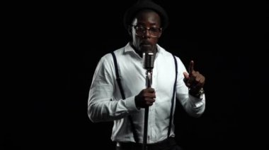 Afro-Amerikan şarkı ve müzik mikrofondan dans. Siyah arka plan. Ağır çekim. Yakın çekim