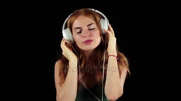 Dívka poslouchá její oblíbenou hudbu přes sluchátka. Černé pozadí. Zpomalený pohyb