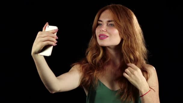 Meisje maakt selfie op haar smartphone. Zwarte achtergrond. Slow motion — Stockvideo