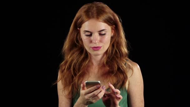 Mädchen betrachtet das Foto auf ihrem Handy. schwarzer Hintergrund. Zeitlupe — Stockvideo