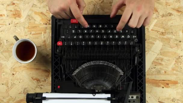 Чоловічі руки друкують текст книги на друкарській машинці. Вид зверху — стокове відео