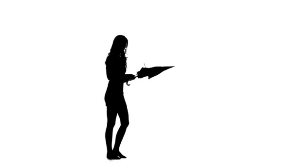 Girl opened the umbrella and tried to close it. White background. Silhouette — Stock Video