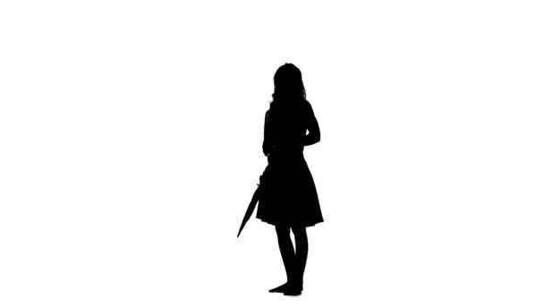 Girl opens an umbrella and raises her leg up. White background. Silhouette — Stock Video