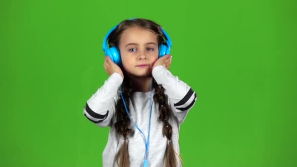 ヘッドフォンの子は音楽を聴いています。緑色の画面。スローモーション — ストック動画