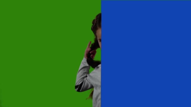 Child looks out from behind the blue board and laughs. Green screen. Slow motion — Stock Video