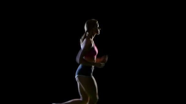 Sportlerin läuft wunderschön in einer halben Drehung auf schwarzem Hintergrund. Silhouette — Stockvideo