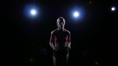 Arkadan aydınlatmalı siluet siyah bir arka plan üzerinde çalışan genç bir kadın. Siluet. Ağır çekim