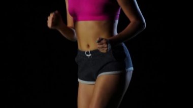 Gövde ve bacaklar siyah bir zemin üzerine bir koşucu. Ağır çekim. Yakın çekim