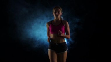 Işıklı içinde çalışan sevimli gülümseyen küçük hanım dumanlı siyah bir ekranda. Ağır çekim