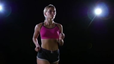 Yarım silindirik soldan sağa iyi görünümlü kız arkadan aydınlatmalı siyah arka plan üzerine çalışan çekim. Ağır çekim. Yakın çekim