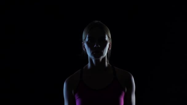 Jong in roze top meisje loopt op een zwarte achtergrond. Silhouet. Slow-motion. Close-up — Stockvideo