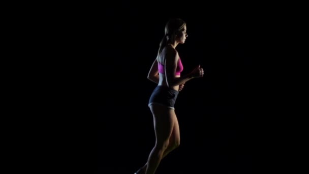 Menina correndo levando um estilo de vida saudável em um fundo preto. Movimento lento — Vídeo de Stock