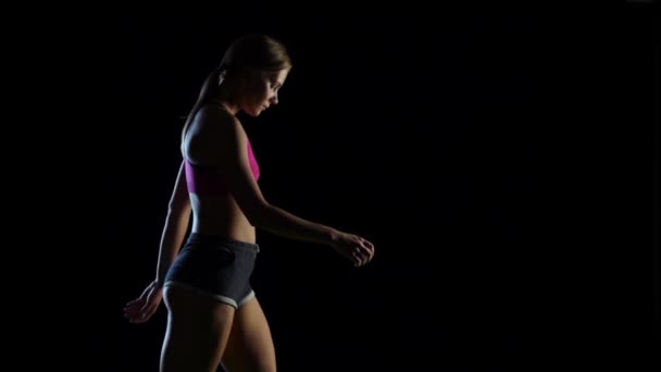 Girl goes leading a healthy lifestyle on a black background. Slow motion — Stock Video