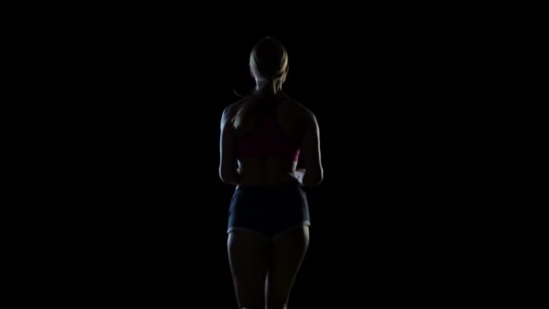 Vue de dos sur une femme courant sur un écran noir. Silhouette. Mouvement lent — Video