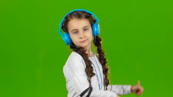 Ребёнок в наушниках слушает музыку. Зеленый экран — стоковое видео