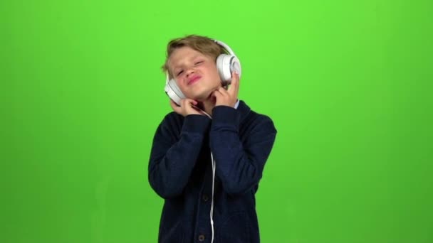 Kind in de hoofdtelefoon luistert naar muziek. Groen scherm. Slow motion — Stockvideo