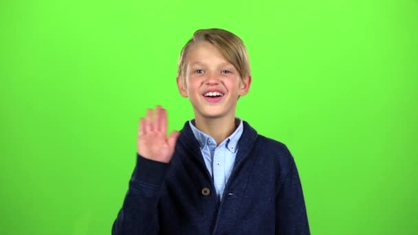 Мальчик машет рукой и звонит другу. Зеленый экран. Медленное движение — стоковое видео