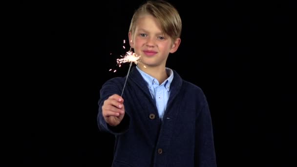 El niño sostiene un fuego de bengala en su mano. Fondo negro. Movimiento lento — Vídeos de Stock
