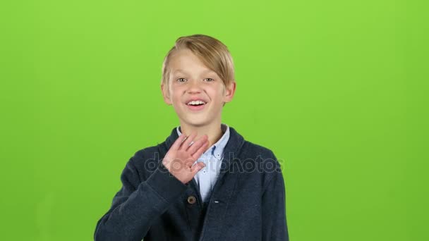 Мальчик машет рукой и звонит другу. Зеленый экран — стоковое видео